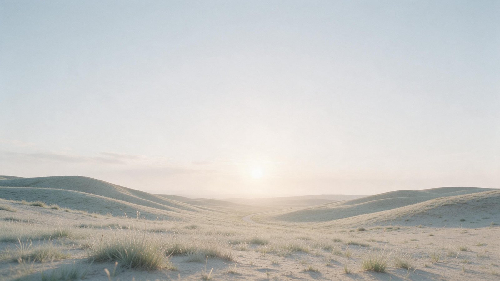 Soft dawn light over open rolling hills with a path curving toward the horizon